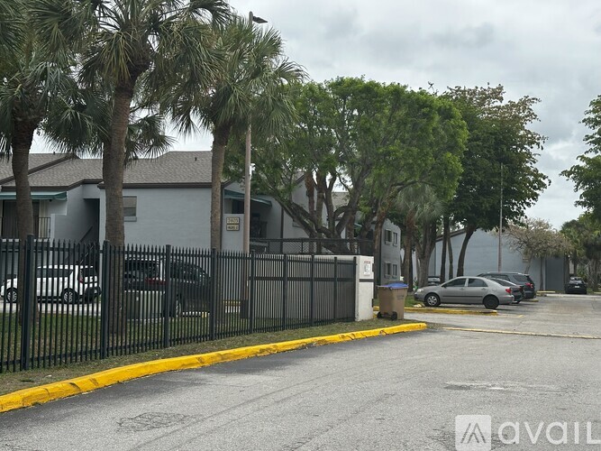 A street view with a black fence and a car parked on the side.