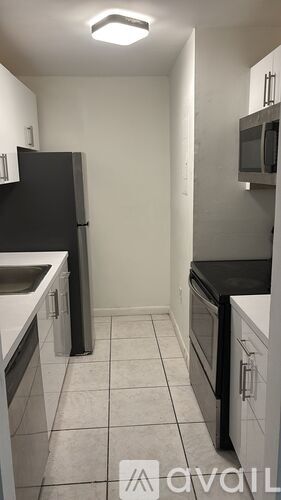A kitchen with a black refrigerator and white cabinets.