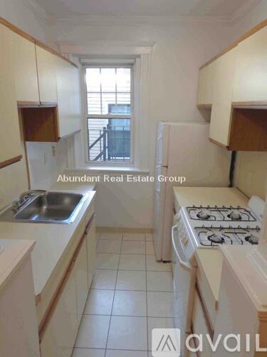 A kitchen with a stove, sink, and cabinets.