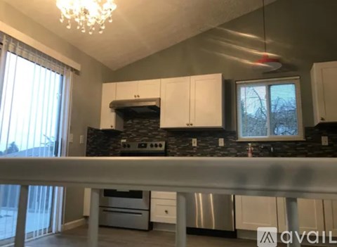 A kitchen with white cabinets and a black backsplash.