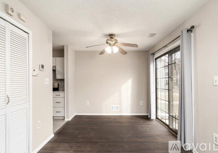 A room with a ceiling fan and sliding glass doors.