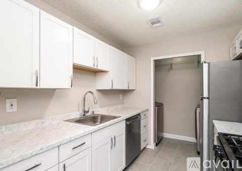 A kitchen with white cabinets and a marble countertop.
