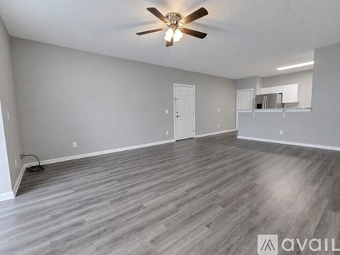 A spacious room with wooden flooring and a ceiling fan.
