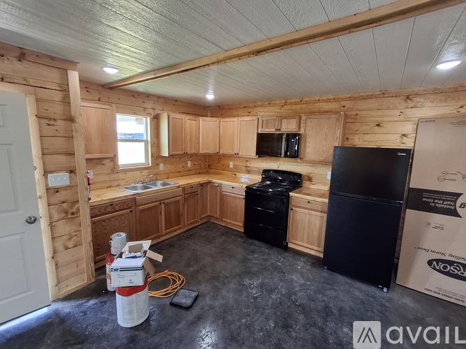 A kitchen area with wooden cabinets and a black refrigerator.
