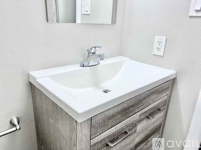 A white sink with a silver faucet is on a wooden cabinet.
