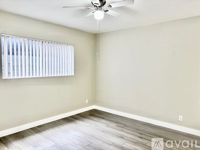 A room with a ceiling fan and a window with blinds.
