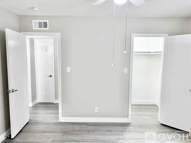 A white interior room with a door on the left and a white refrigerator on the right.