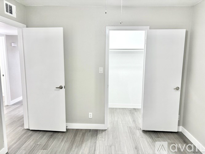 A white door is open to a room with a grey floor.