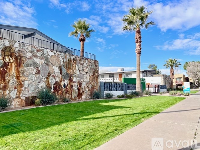 A stone wall with a palm tree in front of a building.