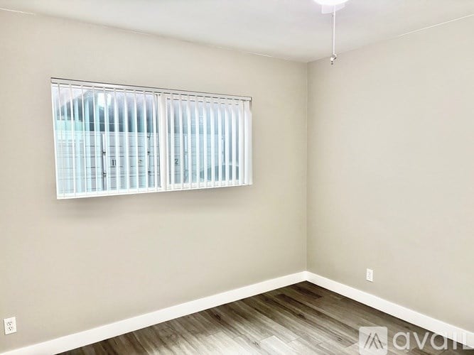 A room with a window covered by white blinds.