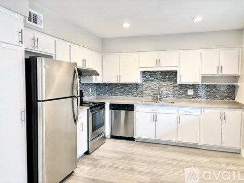 A kitchen with a stainless steel refrigerator and white cabinets.