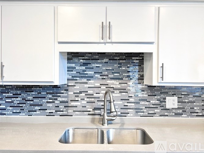 A modern kitchen with a stainless steel sink and white cabinets.