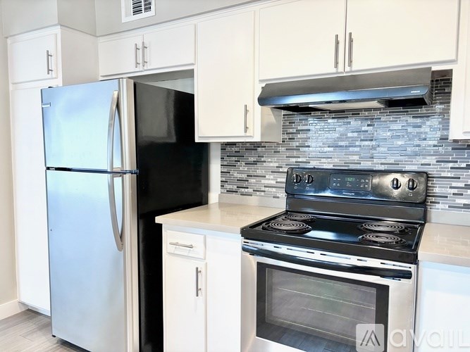 A kitchen with a stainless steel refrigerator and a stove top oven.