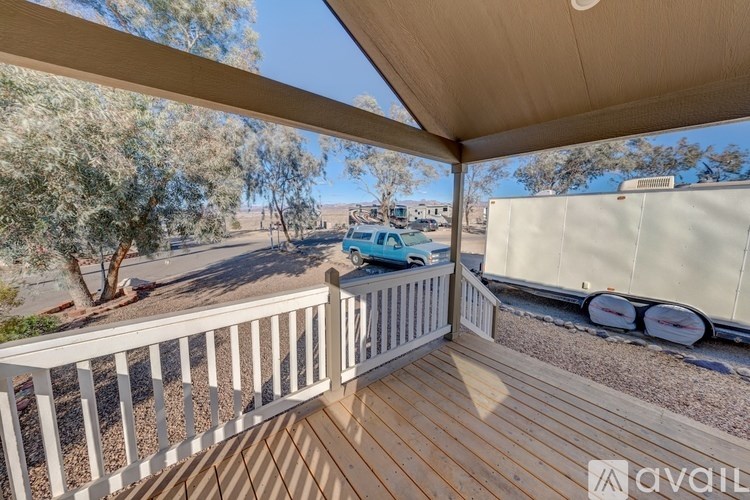 A balcony with a white railing and a view of a car and trees.