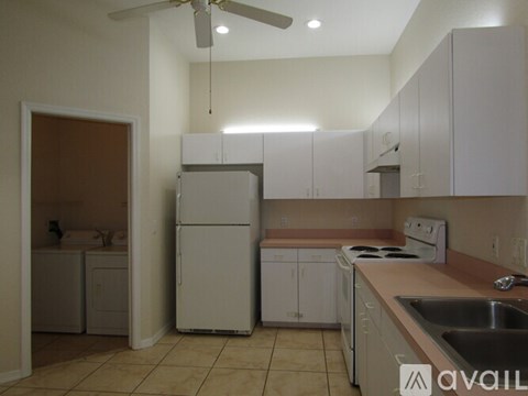 A kitchen with white cabinets and a white fridge.