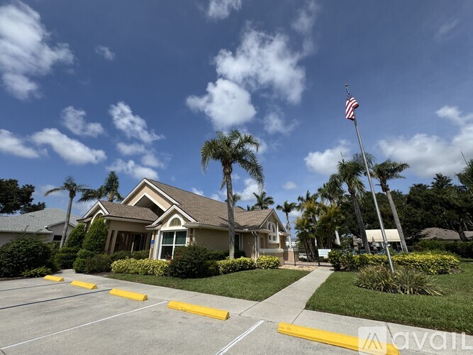 A house with a flag on a pole stands in front of a row of palm trees.