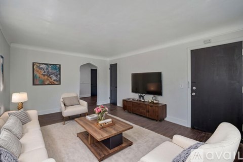A living room with a white couch, a wooden coffee table, and a painting on the wall.