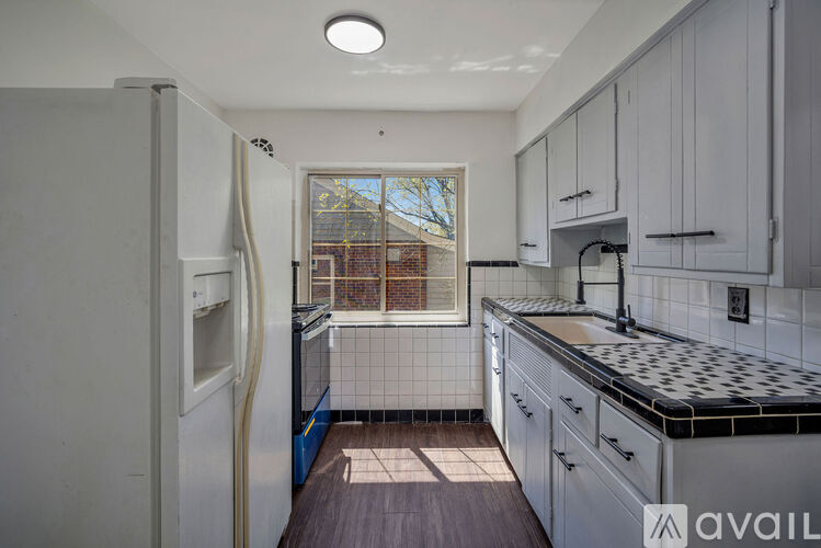 A kitchen with white cabinets and a black and white tiled backsplash.
