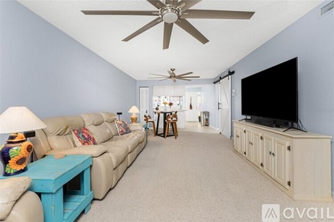 A living room with a large couch and a television on a cabinet.