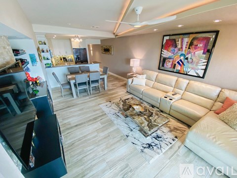 A living room with a white couch and a painting on the wall.