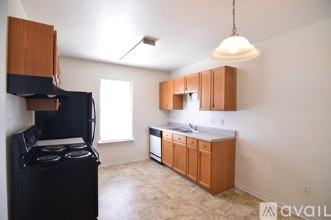 A kitchen with a black stove top oven and wooden cabinets.