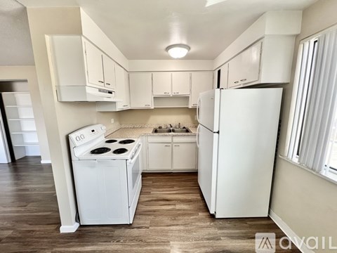 A white kitchen with a stove, refrigerator, and cabinets.