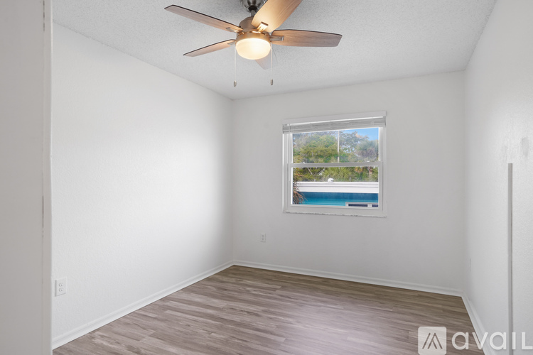 A room with a ceiling fan and a window overlooking a pool.