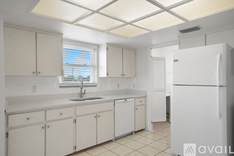 A kitchen with white cabinets and a white refrigerator.