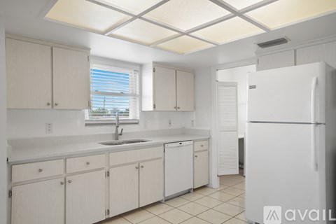 A kitchen with white cabinets and a white refrigerator.