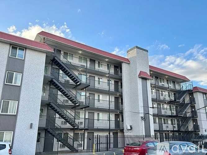 A modern apartment building with a red roof and a car parked in front.