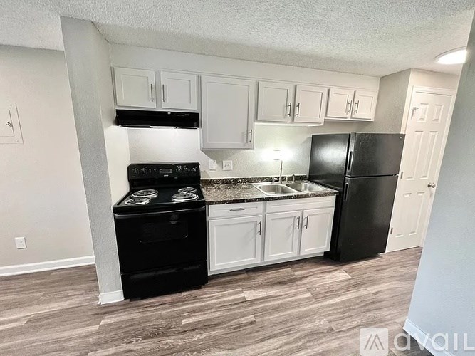 A kitchen with black appliances and white cabinets.