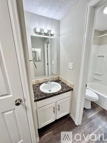 A bathroom with a sink, mirror, and toilet.