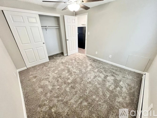 A carpeted room with a ceiling fan and two closets.
