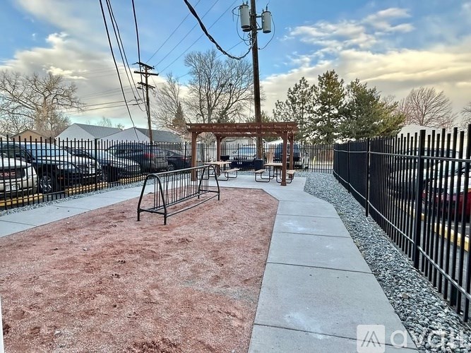 A red brick pathway leads to a black gate.
