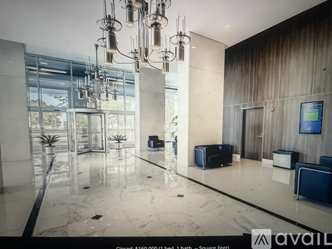 A spacious lobby with a marble floor and a large chandelier.
