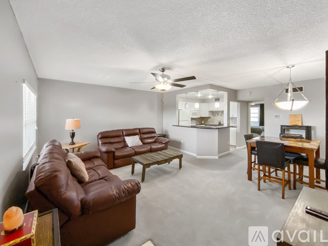 A living room with a brown leather couch and a wooden table.
