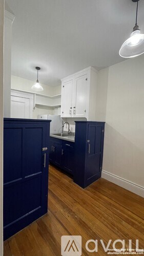 A kitchen with dark blue cabinets and a wooden floor.