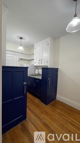 A kitchen with white cabinets and a blue island.