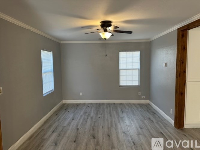 A room with a ceiling fan and wooden flooring.