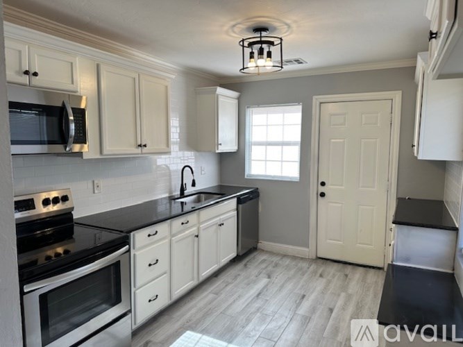 A kitchen with white cabinets and black countertops.