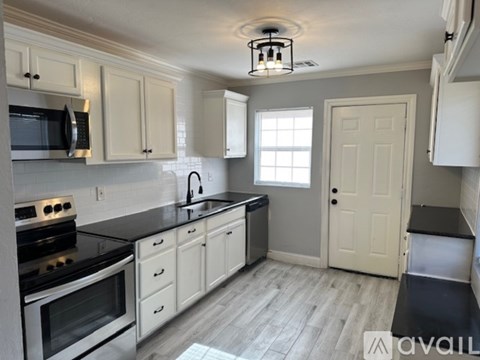 A kitchen with white cabinets and black countertops.