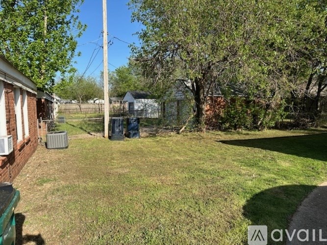 A backyard with a green lawn and trees.