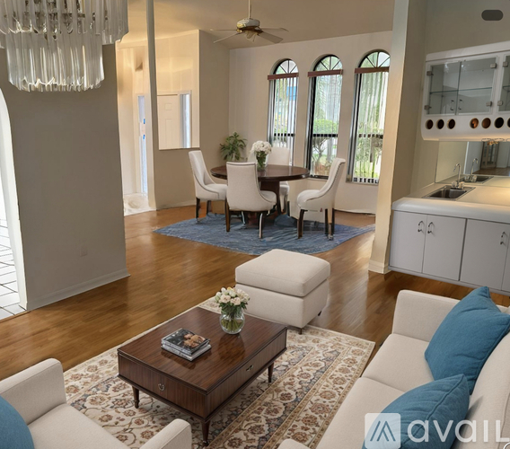 A living room with a white couch, a coffee table, and a dining table with chairs.