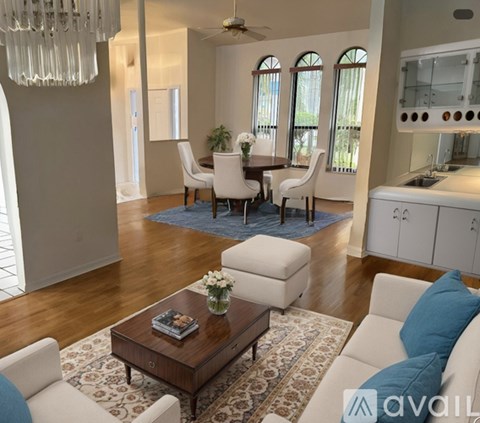A living room with a white couch, a coffee table, and a dining table with chairs.
