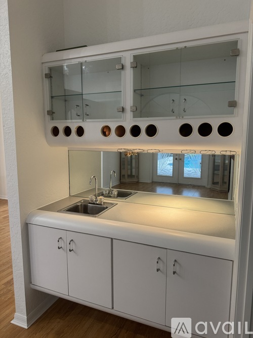 A modern kitchen with a white cabinet and a large mirror above the sink.