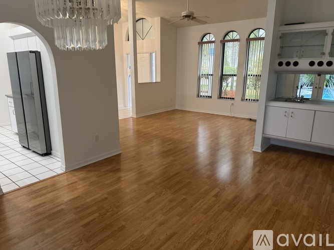 A spacious room with wooden floors and a chandelier.