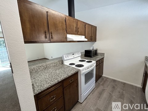 A kitchen with a white stove top oven and wooden cabinets.