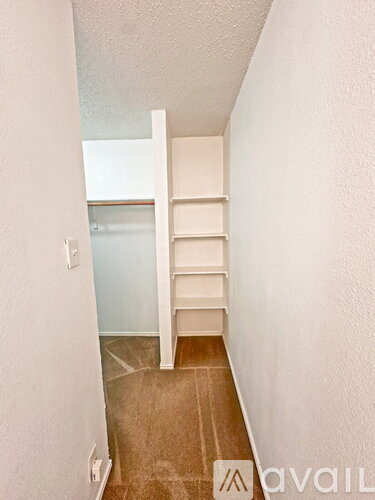 A room with a white shelf and a light switch on the wall.