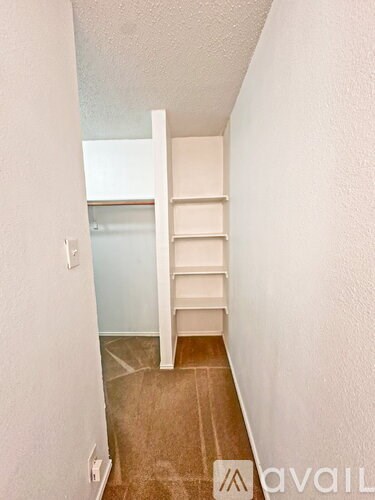 A room with a white shelf and a light switch on the wall.