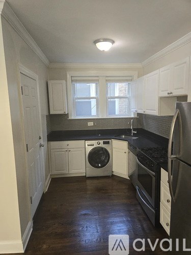 A kitchen with white cabinets and a black countertop.